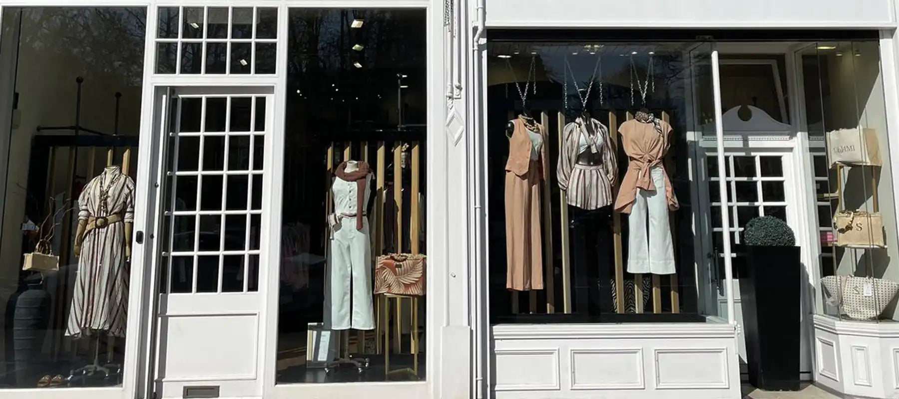 A boutique storefront with multiple mannequins displaying stylish clothing and accessories.